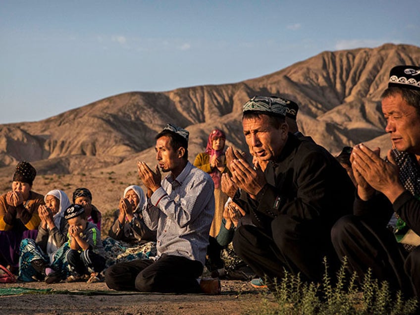 A Uyghur family pray at the grave of a loved one on the morning of the Corban Festival on