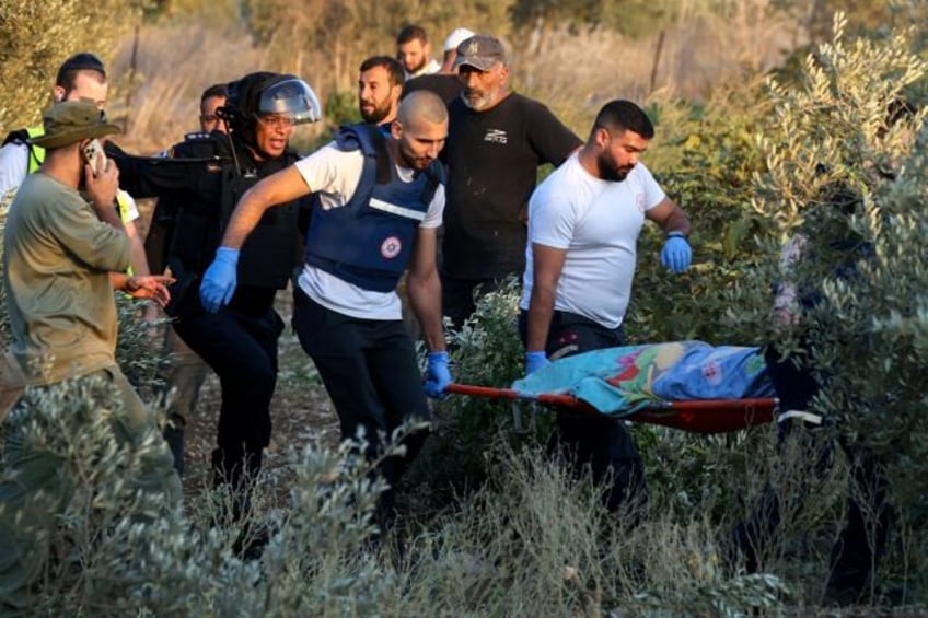 First responders carry the shrouded body of a woman killed when a rocket fired from Lebano