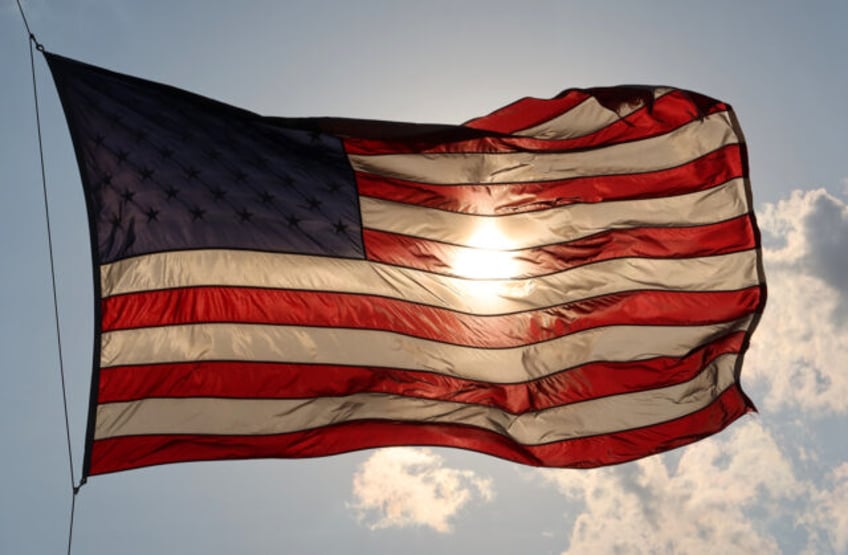 HOBOKEN, NJ - MAY 15: The sun sets behind an American Flag on May 14, 2020 in Hoboken, New