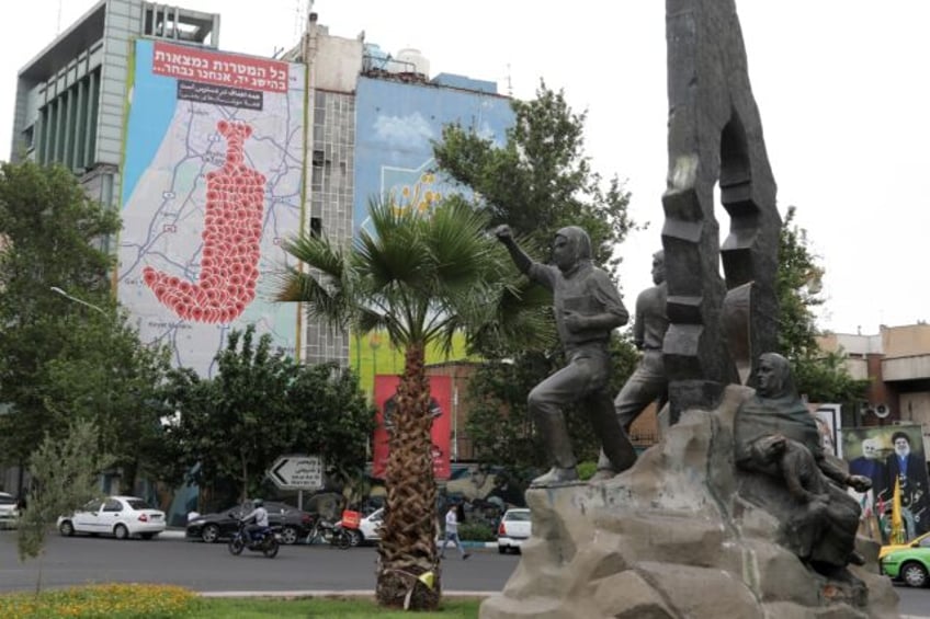 People drive past an anti-Israel billboard in Tehran's Palestine square on May 5, 2025
