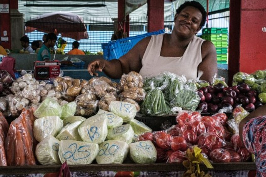 A woman sells vegetables, mostly imported from South Africa, in 2019 at a market in Victor
