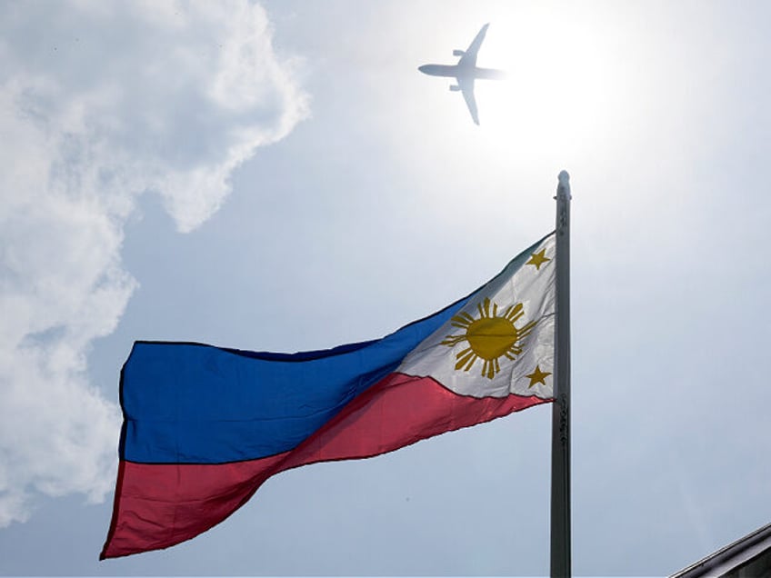 A plane flies above a Philippine flag at the Emilio Aguinaldo Shrine, where Philippine ind