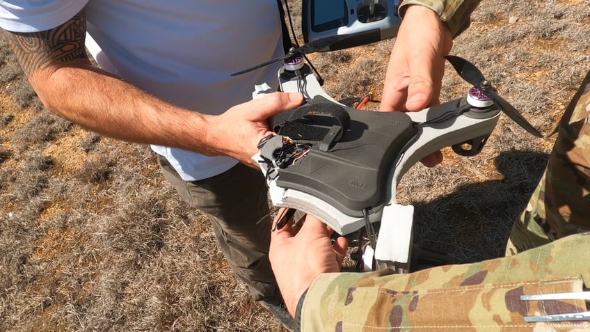 Military men hold a damaged 3D printed drone that can be restored and used again for training purposes. 
