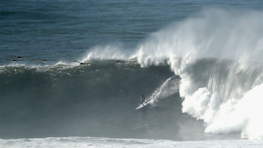 A surfer rides a wave in Half Moon Bay