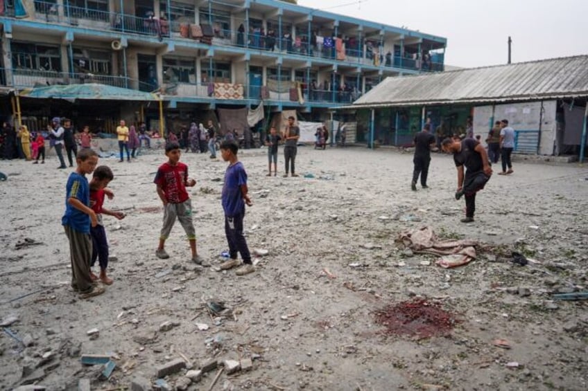 Palestinian boys stand near blood stains at a UN school housing displaced people that was