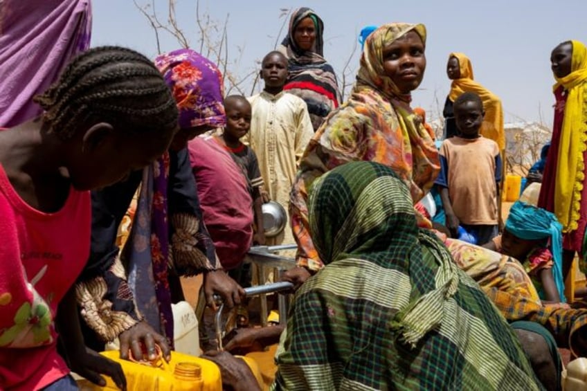 Sudanese refugees gather to fill cans with water in the Farchana refugee camp in Chad on A