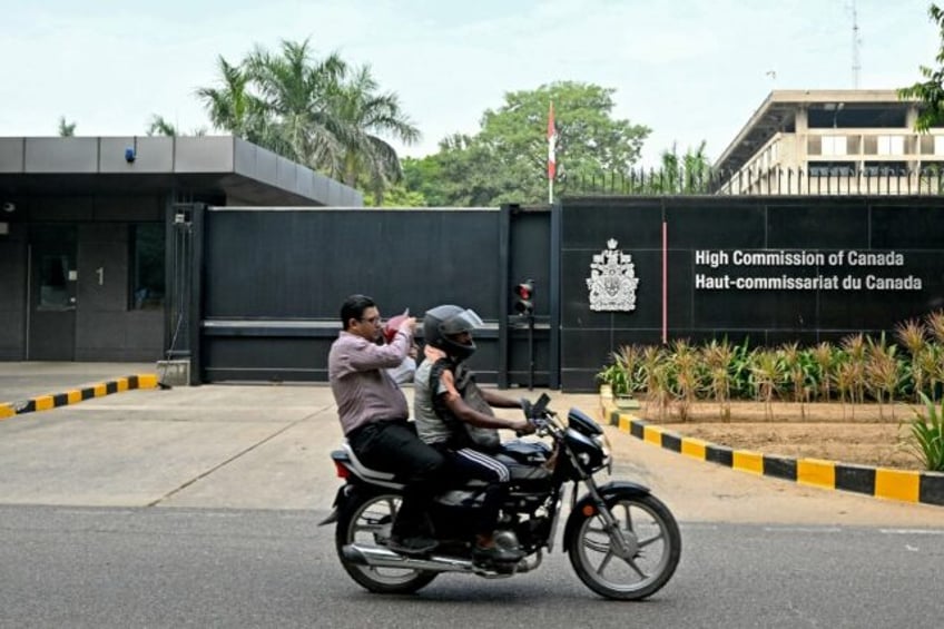 A motorist rides past the entrance of the Canadian High Commission in New Delhi as tension