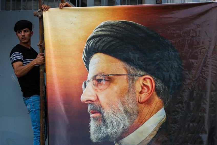 Men hang a huge portrait of Iran's late president Ebrahim Raisi outside the Iranian embass