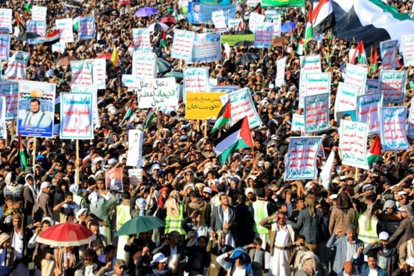 Yemenis lift placards and wave Palestinian flags as they march in the Huthi-run capital Sa