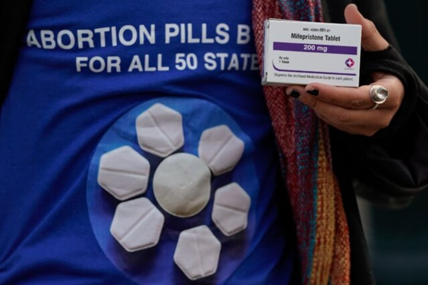 A pro-abortion rights activist holds a box of mifepristone during a rally in front of the