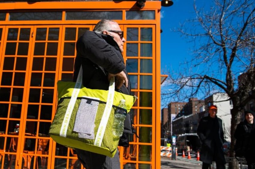 A customer carries his own reusable bag after shopping at a local supermarket on March 1,