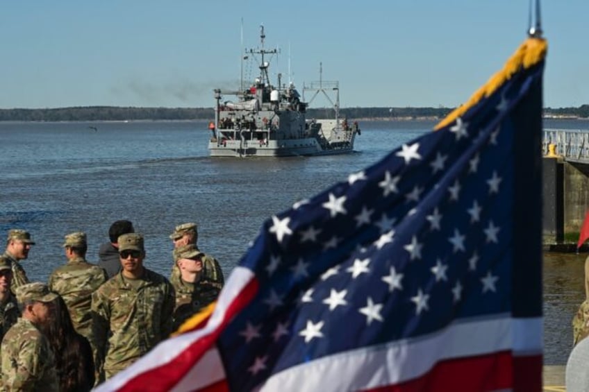 US Army soldiers stand near an American flag as the USAV Wilson Wharf departs for an opera