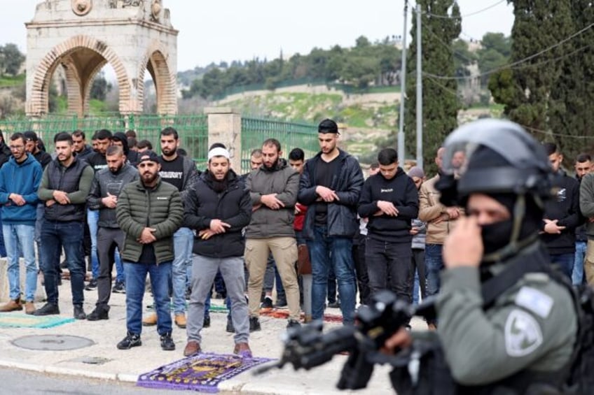 Israeli security forces stand guard as Palestinian Muslims perform Friday Noon prayers on