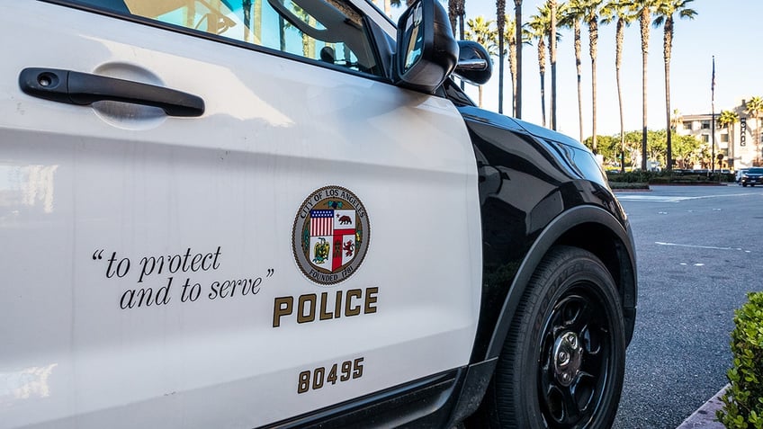 Los Angeles, USA - Close-up on the insignia and slogan of a LAPD vehicle, with the reflection of Union Station's tower visible in the car's window.