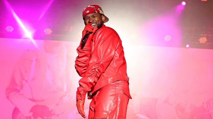 Usher performing on stage in a red leather jumpsuit