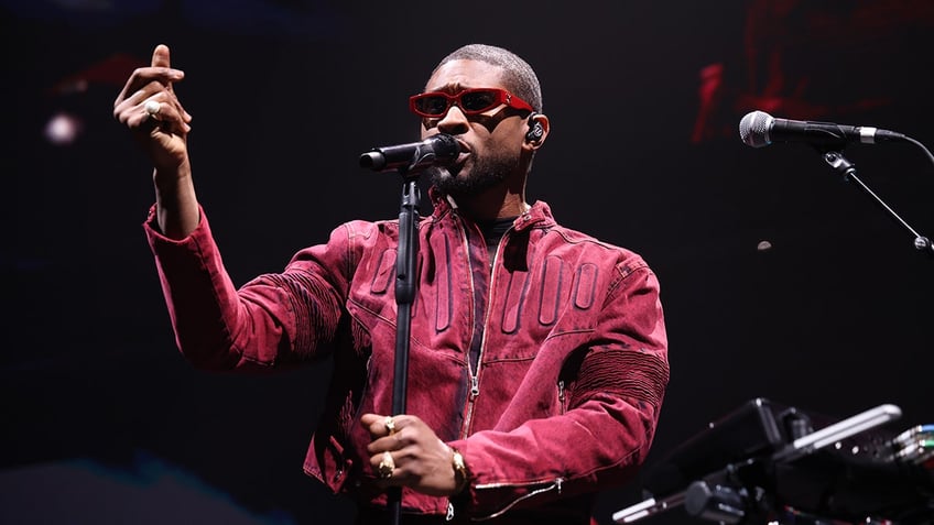 Usher performing onstage in sunglasses