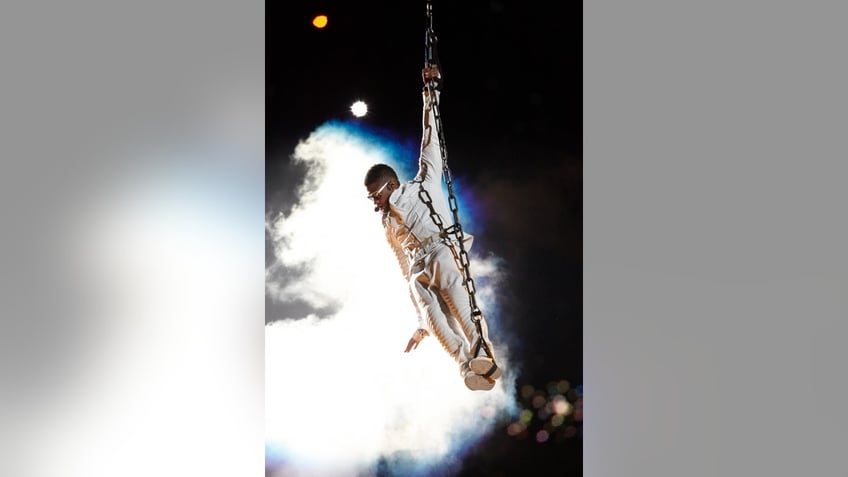Usher holding onto a rope during the Super Bowl Halftime show 2011