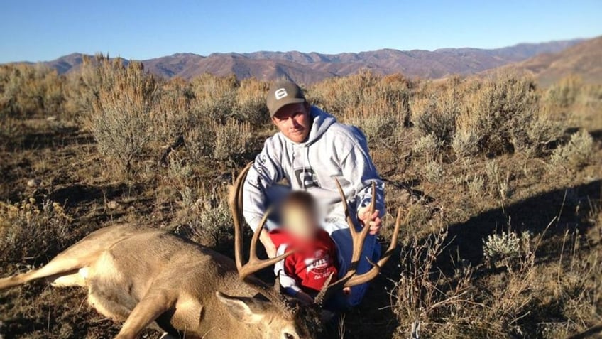 Eric Richins holding a deer with his son