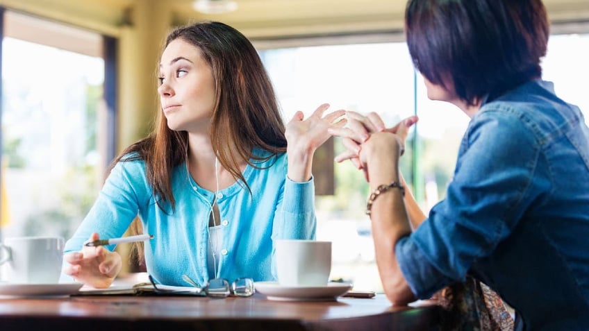 Two women have disagreement at table.