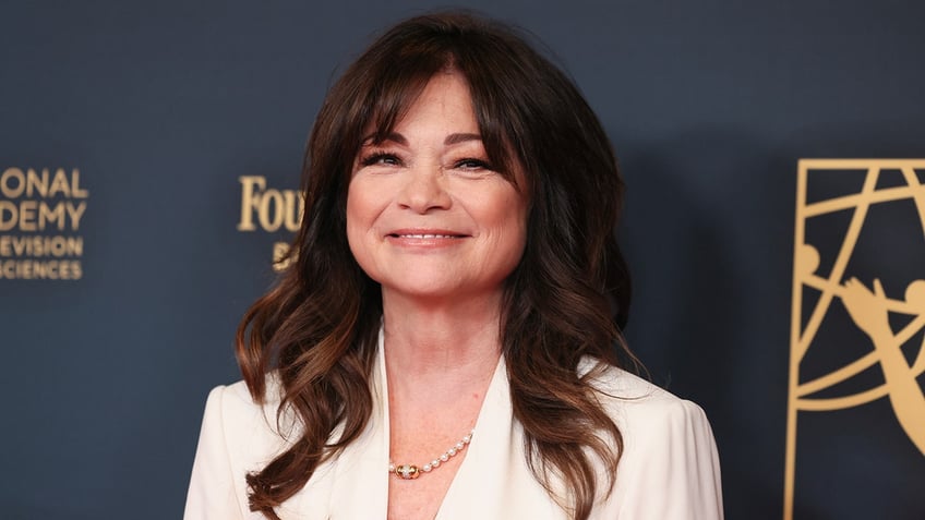 Valerie Bertinelli smiles in a white blouse on the carpet