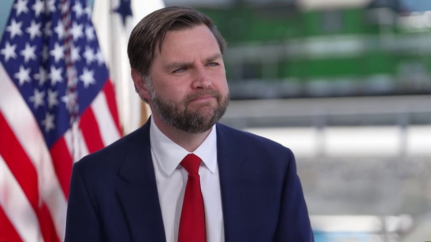 JD Vance smiling with an American flag in the background
