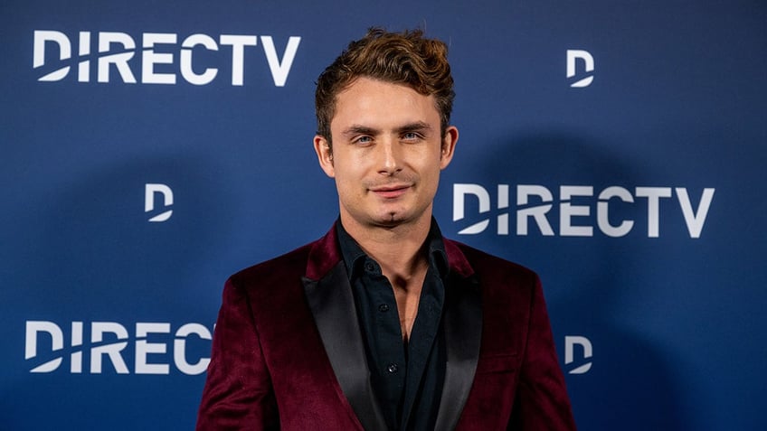 James Kennedy walks the red carpet wearing a crimson suit