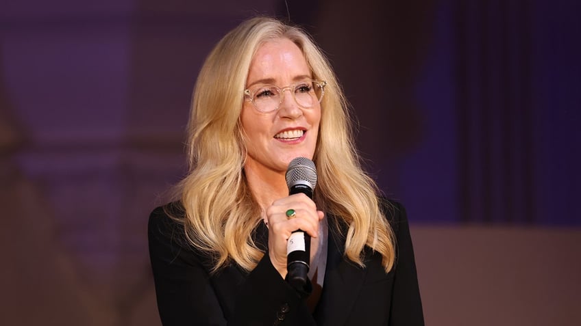 Felicity Huffman smiling with a microphone in her hand