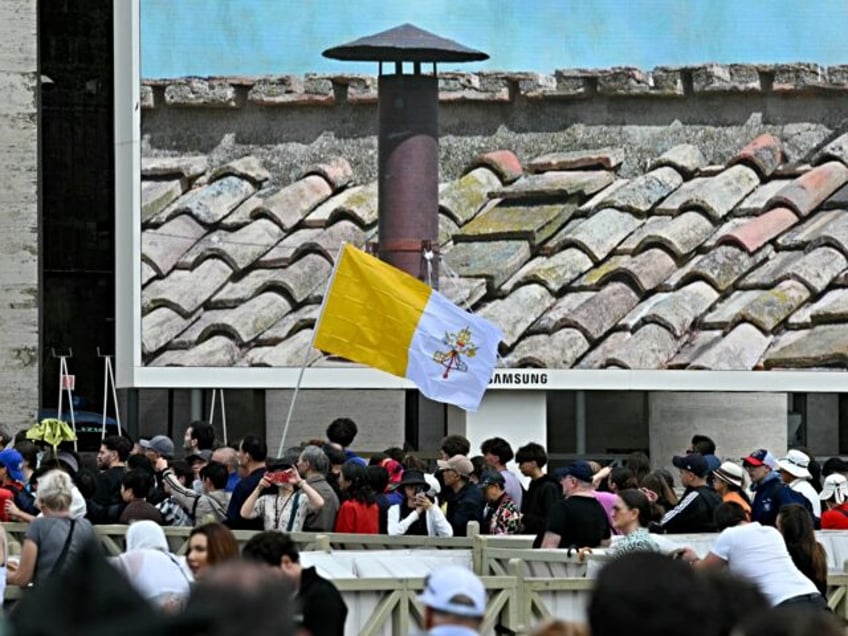 A person walks with a Vatican's flag in St Peter's square on the second day of the conclav