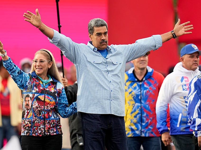 President Nicolas Maduro opens his arms alongside first lady Cilia Flores during his closing election campaign rally in Caracas, Venezuela, Thursday, July 25, 2024. Maduro is seeking re-election for a third term in the July 28 vote. (AP Photo/Fernando Vergara)