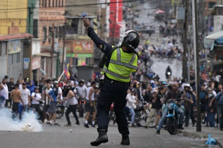 A police officer uses tear gas on demonstrators at a protest against Venezuelan President