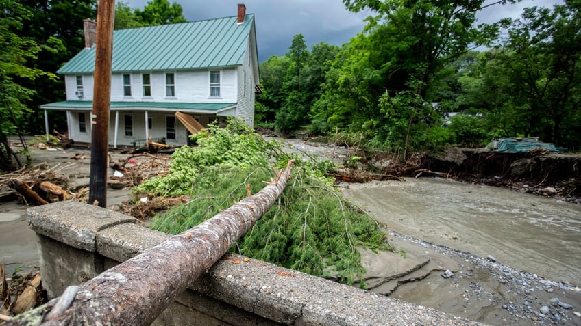 A damaged bridge over the a river is strewn with debris.