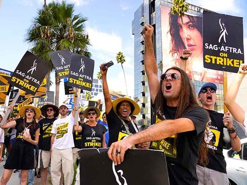 SAG-AFTRA member John Schmitt, second from right, and others carry signs on the picket lin