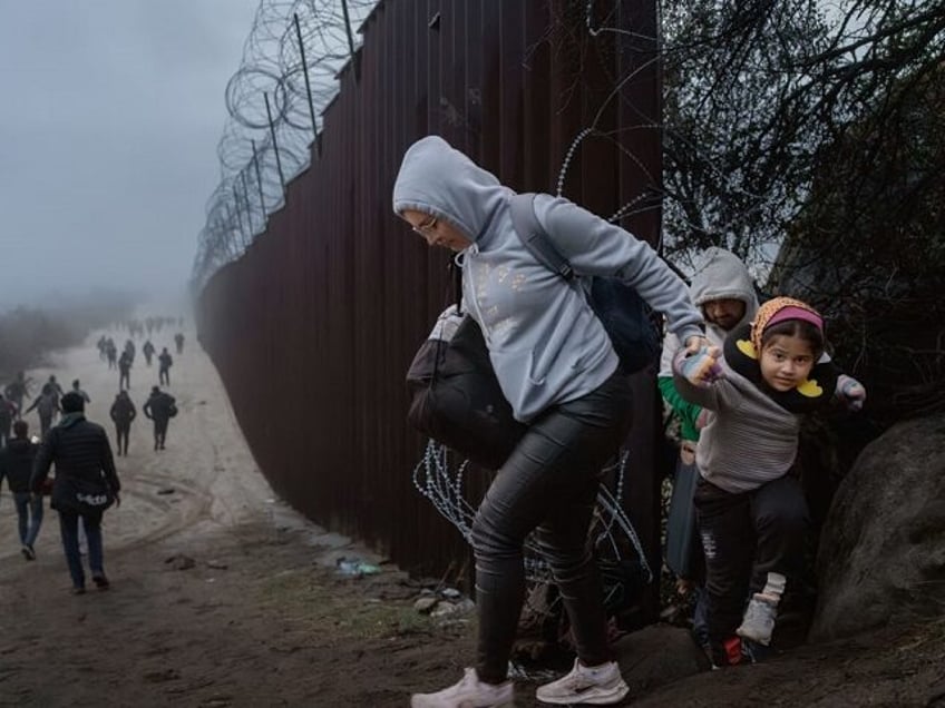 JACUMBA HOT SPRINGS, CALIFORNIA - DECEMBER 22: Migrants cross through a gap in the US-Mexi