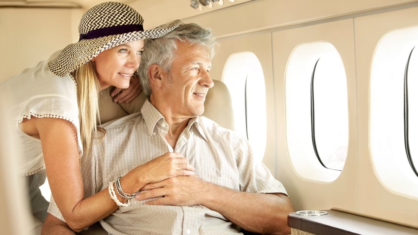 Smiling senior couple on an airplane looking out the window