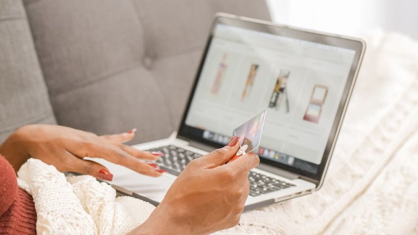 Woman shopping on her laptop while holding her credit card.