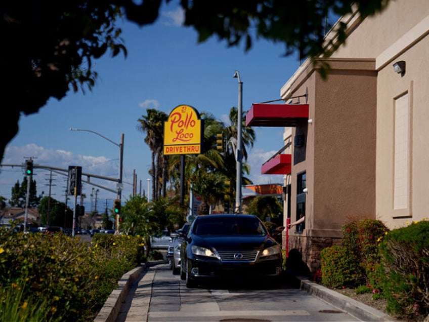 A customer hands a credit card to an employee at the drive-thru of an El Pollo Loco restau