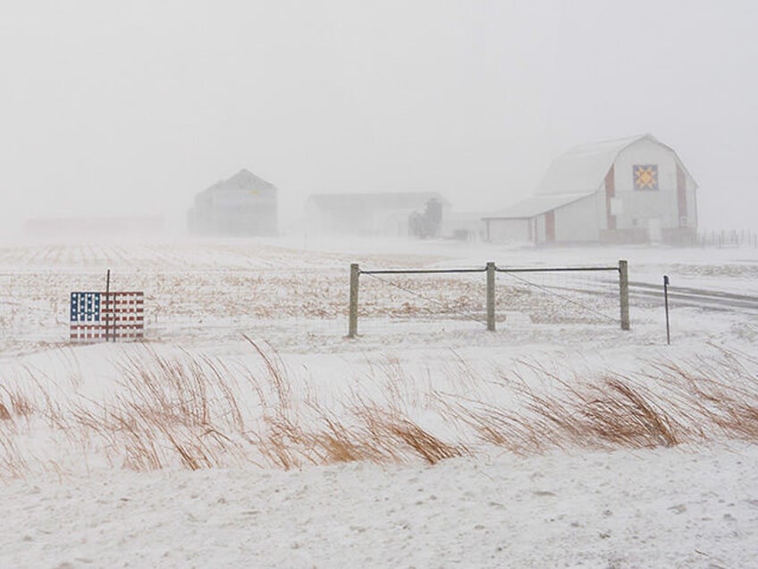 An American flag is mounted on a fence at a farm on U.S. Highway 20 during a blizzard near