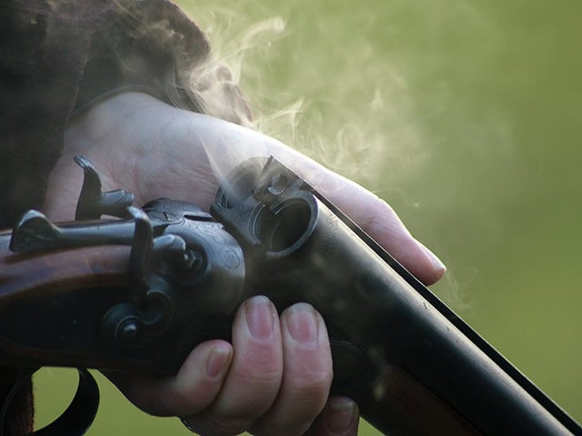 Smoke rises from the barrels of a shotgun.