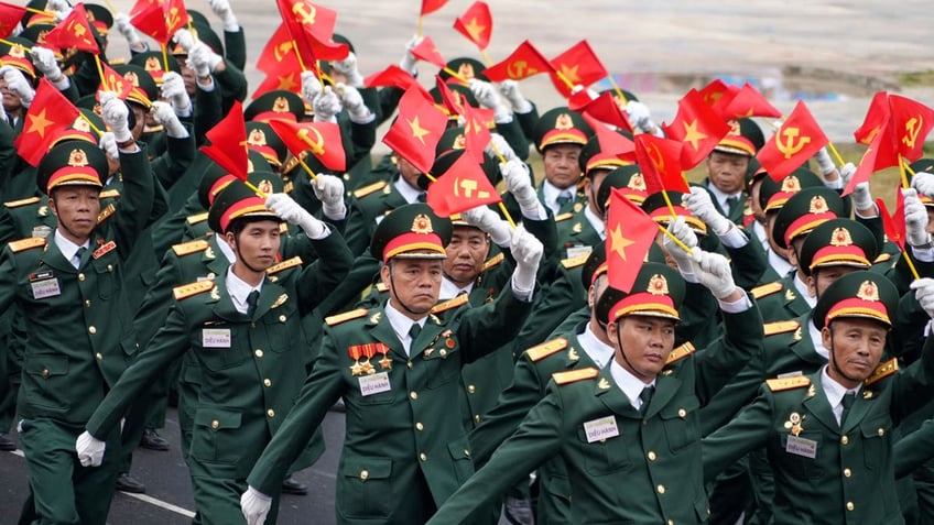Soldiers wave flags and march in a parade commemorating the victory of Dien Bien Phu battle in Dien Bien Phu, Vietnam