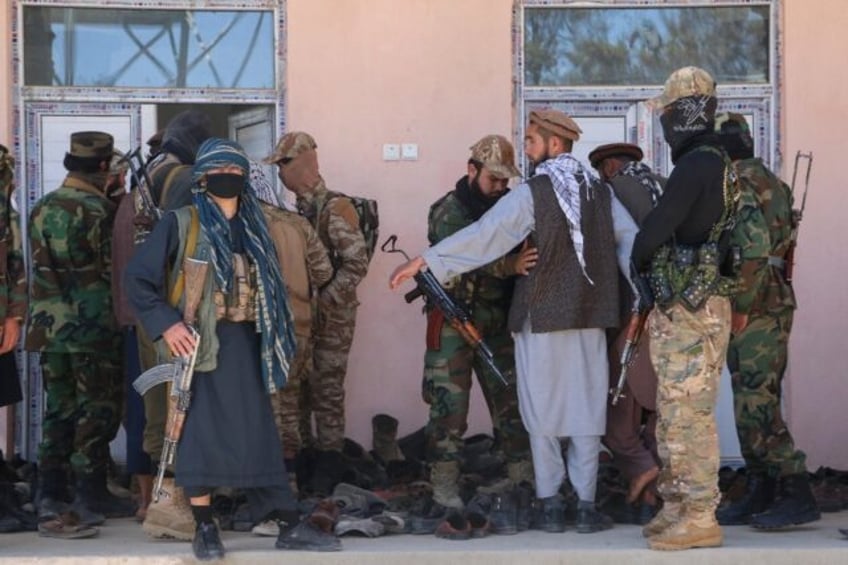 Armed Taliban security personnel frisk people at the entrance of a mosque in Argo district