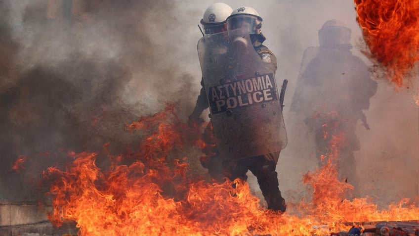 Riot police in Greece react to ignited Molotov cocktails thrown by demonstrators