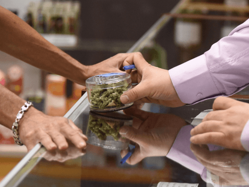 A budtender (right) shows cannabis buds to a customer at the Green Pearl Organics dispensa