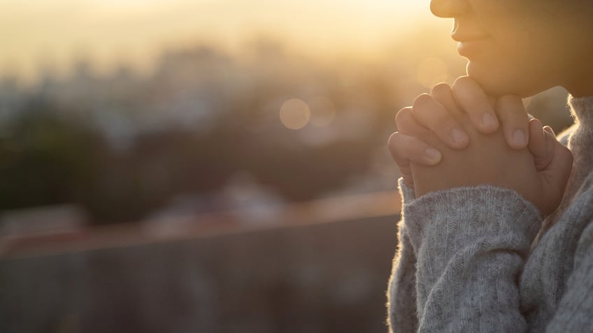 Woman praying in sunset.