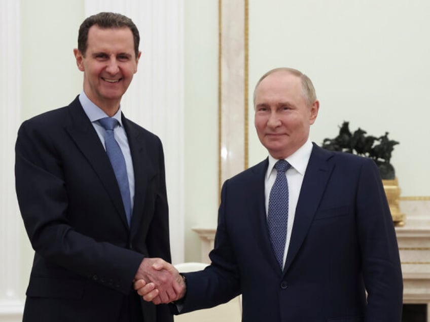 Syrian President Bashar Assad, left, and Russian President Vladimir Putin shake hands duri