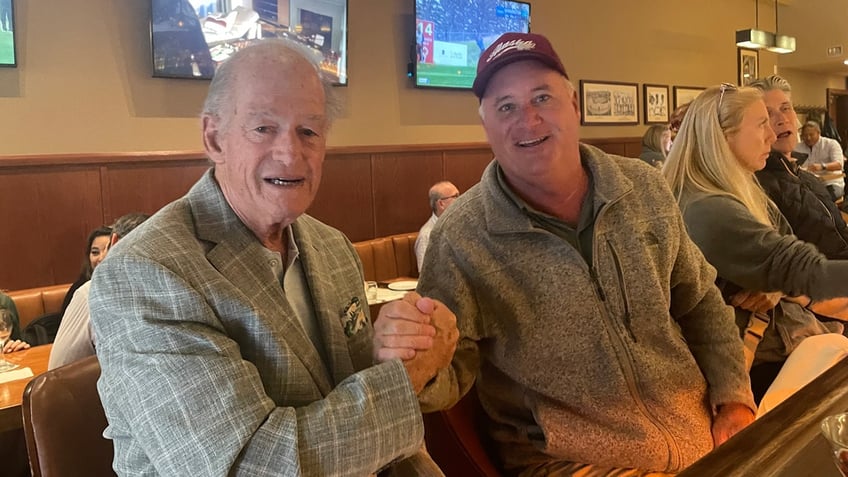 The proprietor of Sam's Tavern (l.), shakes hands with a customer named Scott.