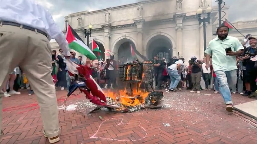 An unnamed patriot reaches down to rescue the American flag from being burned