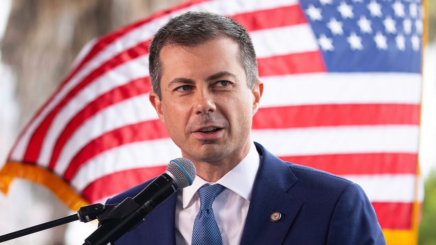 Transportation Sec. Pete Buttigieg with US flag behind him