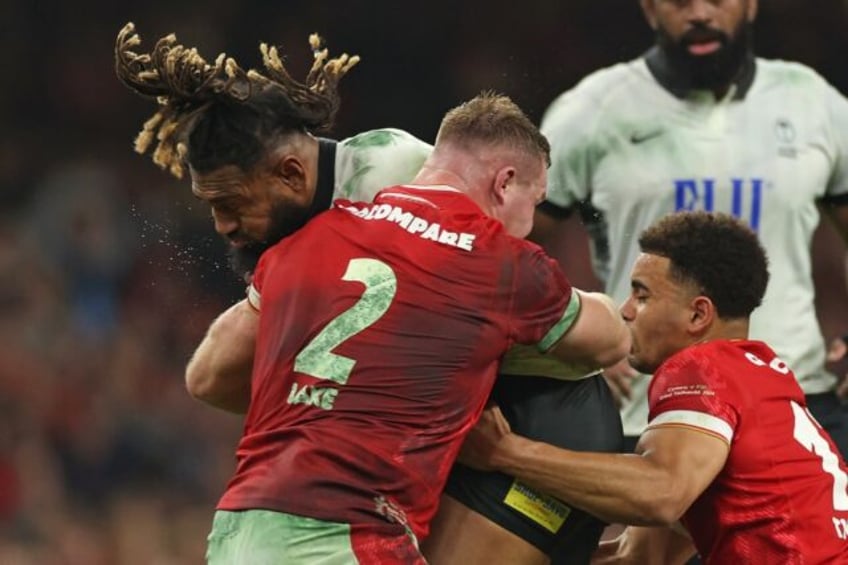 Fiji's centre Waisea Nayacalevu (L) is tackled by Wales' hooker Dewi Lake (C) and Wales' c