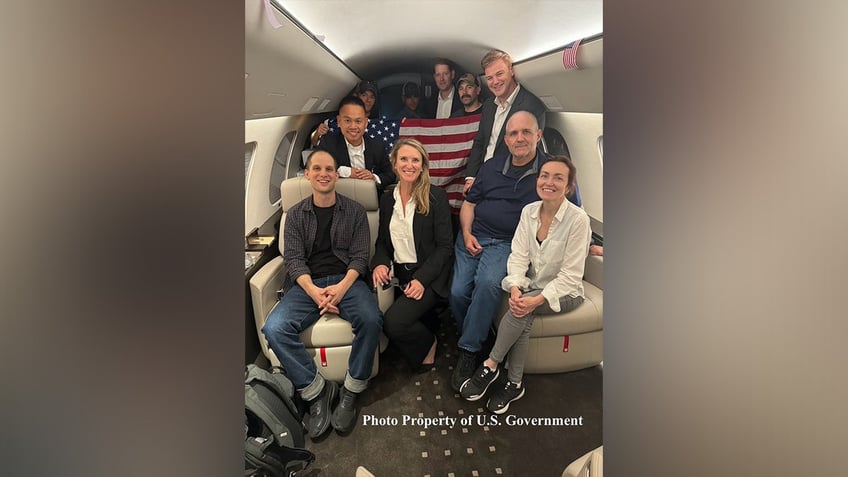 Evan Gershkovich, Alsu Kurmasheva, and Paul Whelan smile aboard an airplane after being released from Russian prison