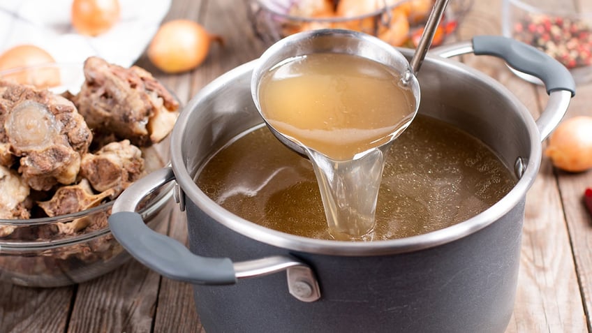 Saucepan with bouillon with a ladle on the table